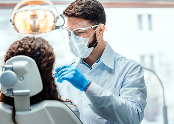Dentist smiling while conducting procedure