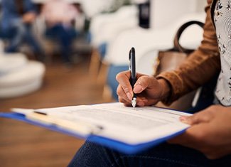 Woman’s hands filling out form on blue clipboard