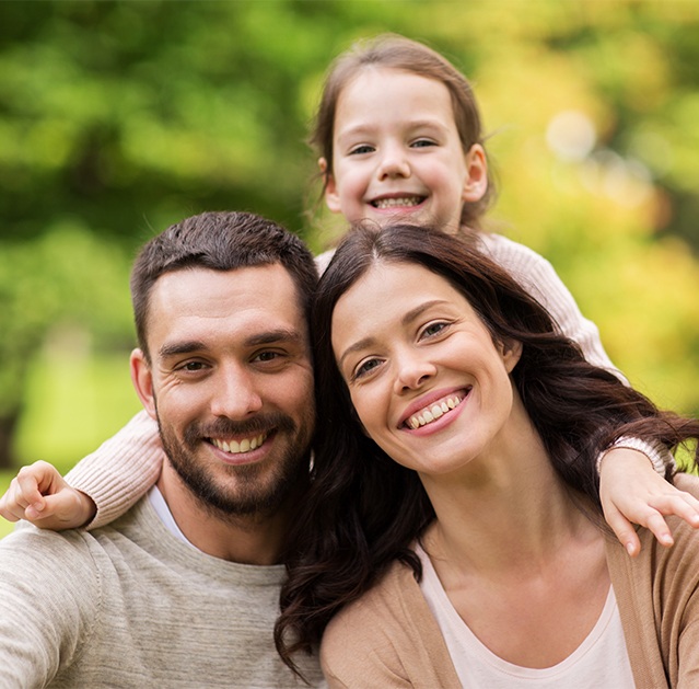 Family of three sharing healthy smiles
