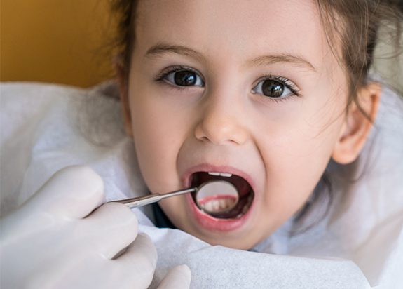 Dentist checking child's tooth colored filling