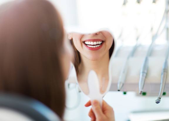 Woman looking in mirror after smile makeover