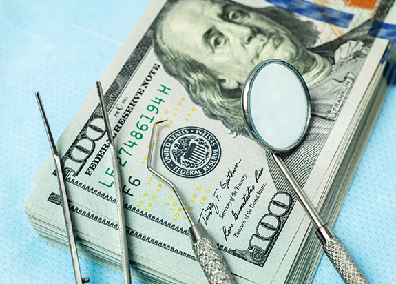 dental instruments sitting on top of a stack of money