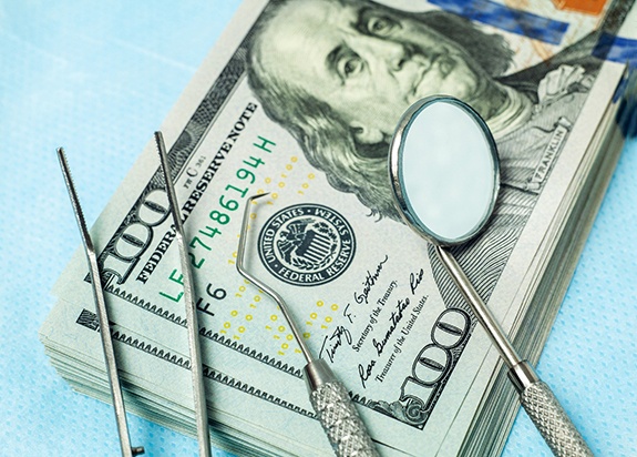 dental instruments sitting on top of a stack of money