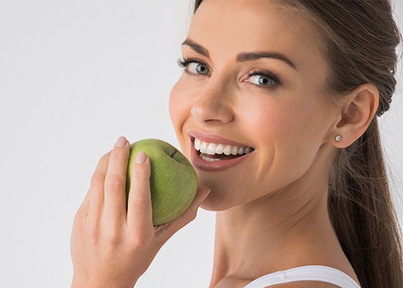 Woman eating an apple after E four D dental restoration treatment