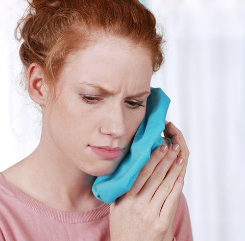 Woman with a toothache in Fresno using an ice pack