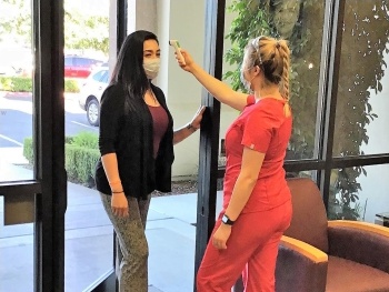 Dental staff member taking temperature of patient