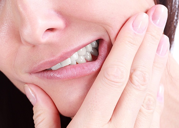 Woman holding jaw in pain before tooth extraction