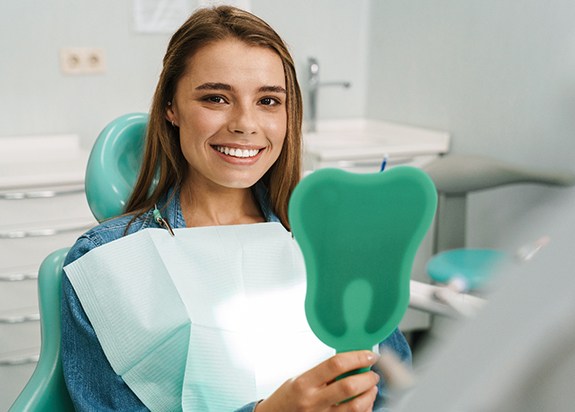 A woman admiring her beautiful smile after a dental treatment
