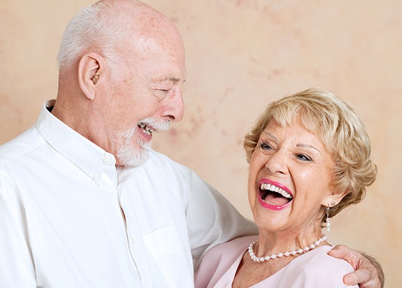 Man and woman laughing together after dental implant supported denture