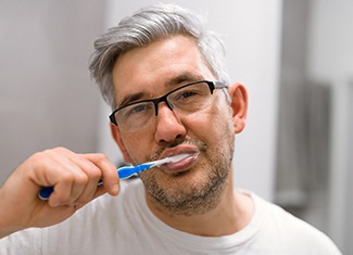Man brushing his teeth during dental implant post-op in Fresno