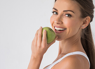 woman biting into a green apple