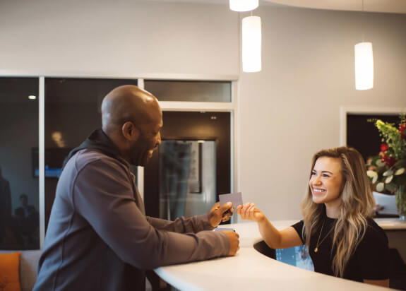 Dental team member greeting patient with a smile at reception desk