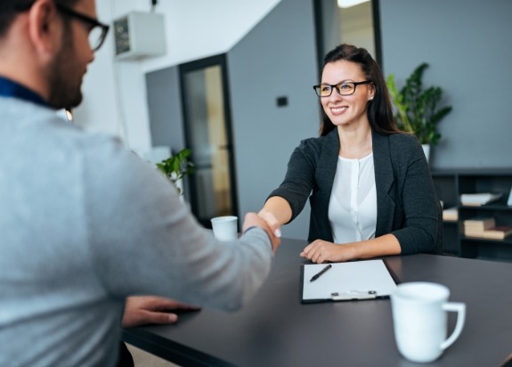 Dental team member greeting patient with a smile at reception desk