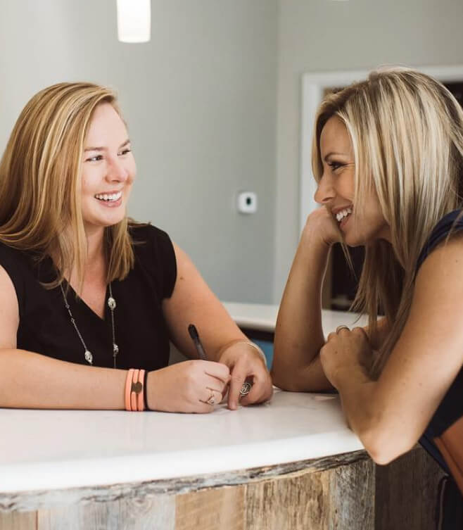 Two dental team members at reception desk