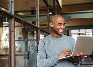 Man smiling while working on laptop in office