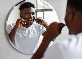 Man smiling while flossing teeth at restaurant