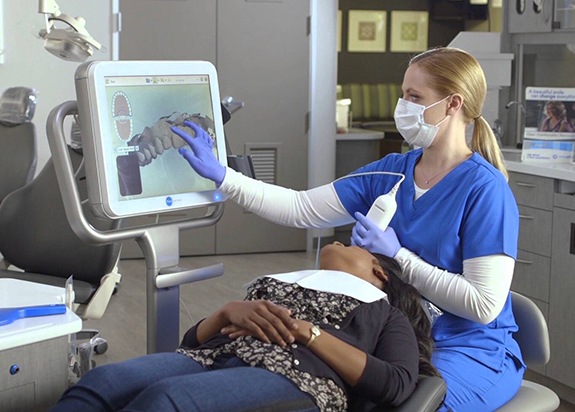 Dentist and patient looking at Invisalign treatment guide on computer screen