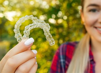 Teen girl smiling while holding clear aligners