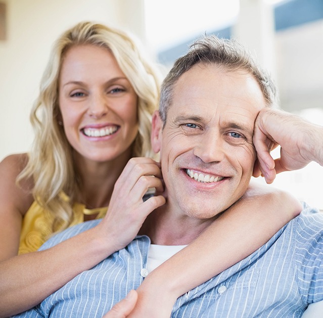 Man and woman smiling together after replacing missing teeth