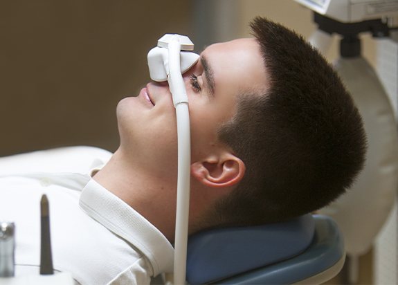 Man with nitrous oxide dental sedation mask relaxing in dental office