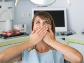 Fearful patient in need of sedation dentistry covering her mouth