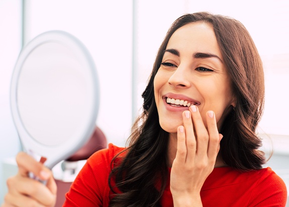 Woman looking in mirror after smile makeover