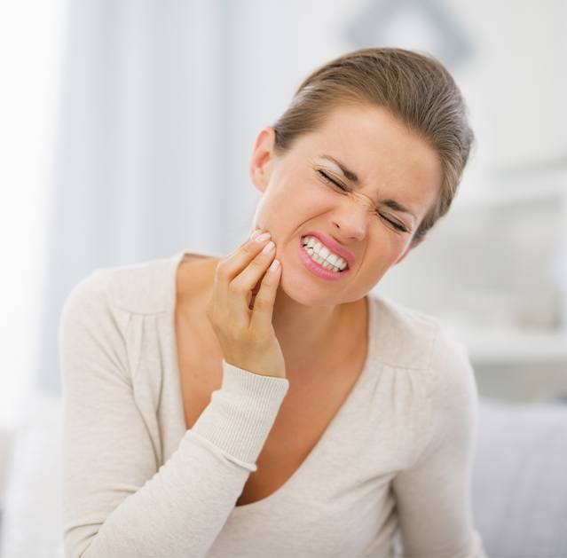 Woman in need of T M J therapy holding jaw in pain