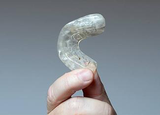 Hand holding an acclusal splint