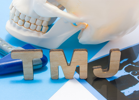 Model skull next to wooden letters spelling out “TMJ”