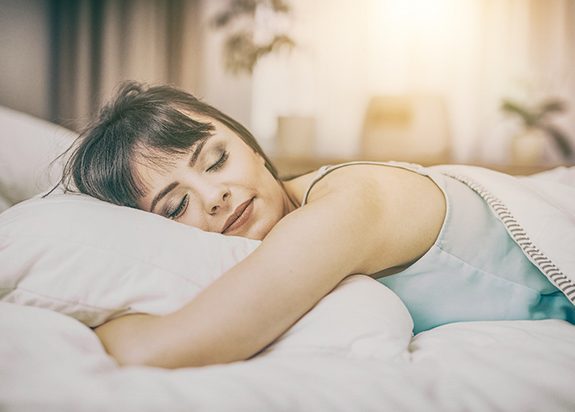 Woman sleeping in bed with Vivos sleep apnea treatment in Fresno, CA