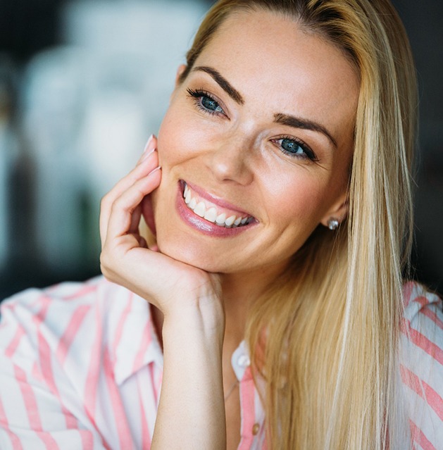 Woman in striped shirt smiling after teeth whitening in Fresno, CA