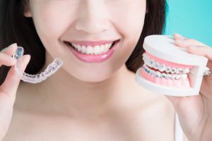 woman holding invisalign and braces