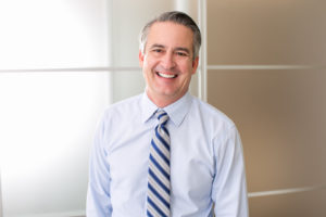 older man in light blue dress shirt and tie smiling with dentures in Fresno 