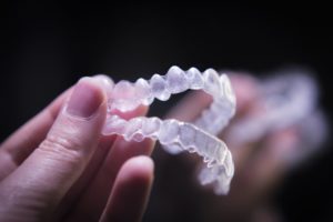 A person holding a pair of clear aligners.